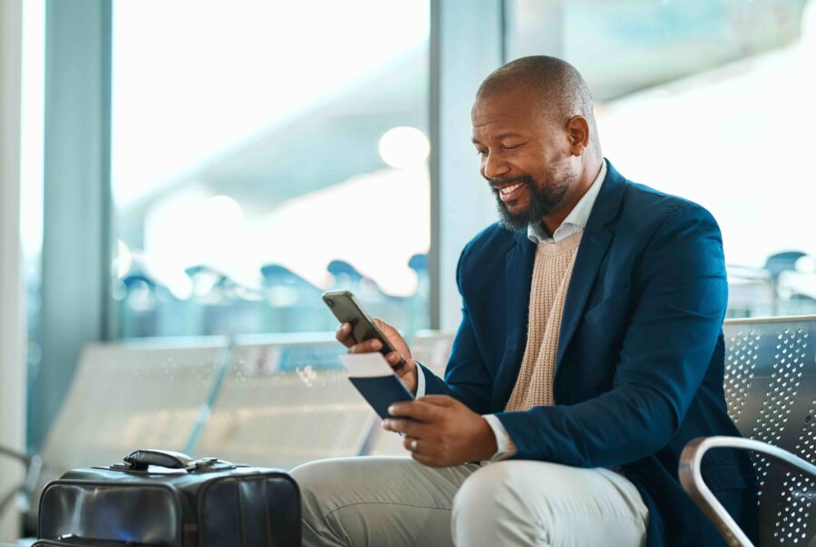 African American business traveler looking at his smartphone in airport terminal