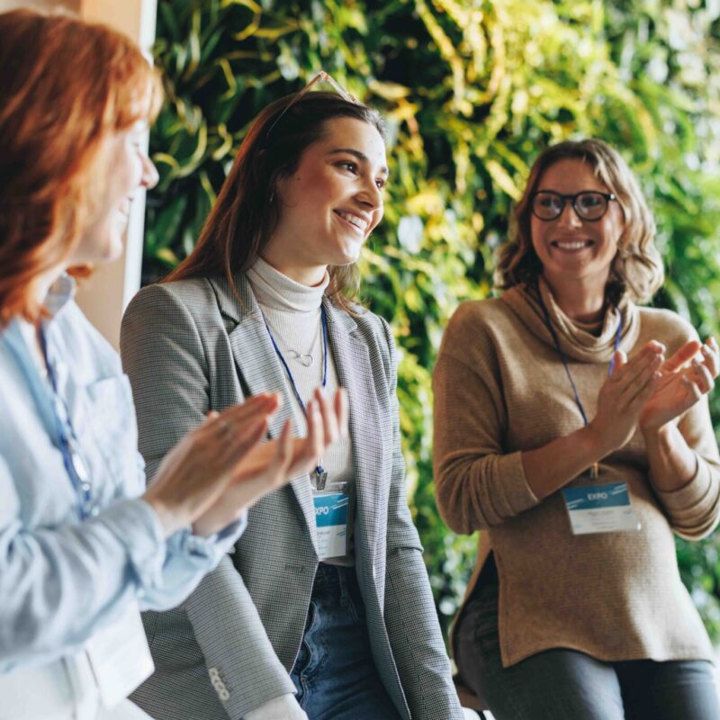 Business women applaud and smile during a successful meeting in an office conference room